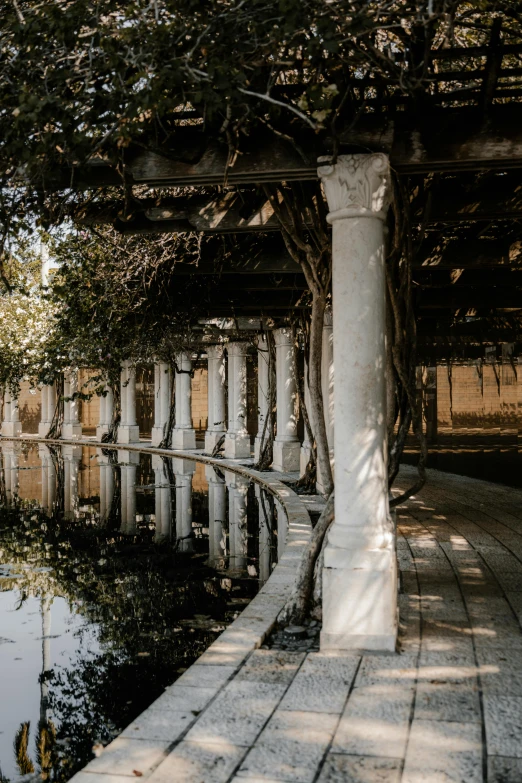 the path next to the water has a row of white pillars on one side