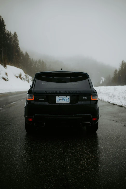 a black car is driving down the road covered in snow