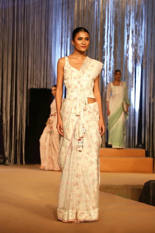 a woman walking down a runway wearing white attire