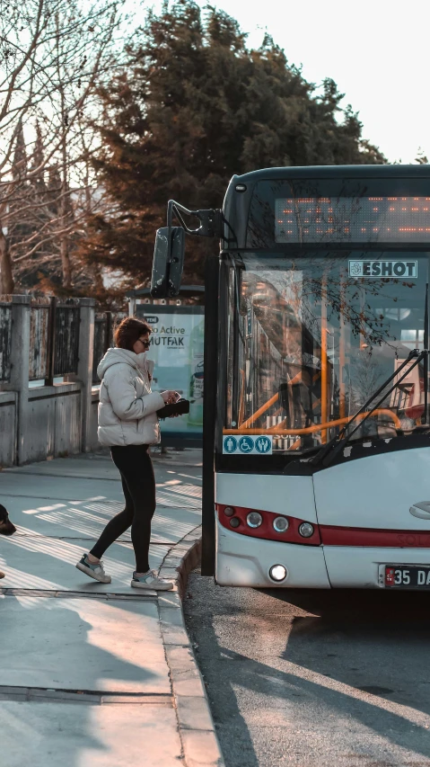 a woman walks past a public transit bus at an intersection