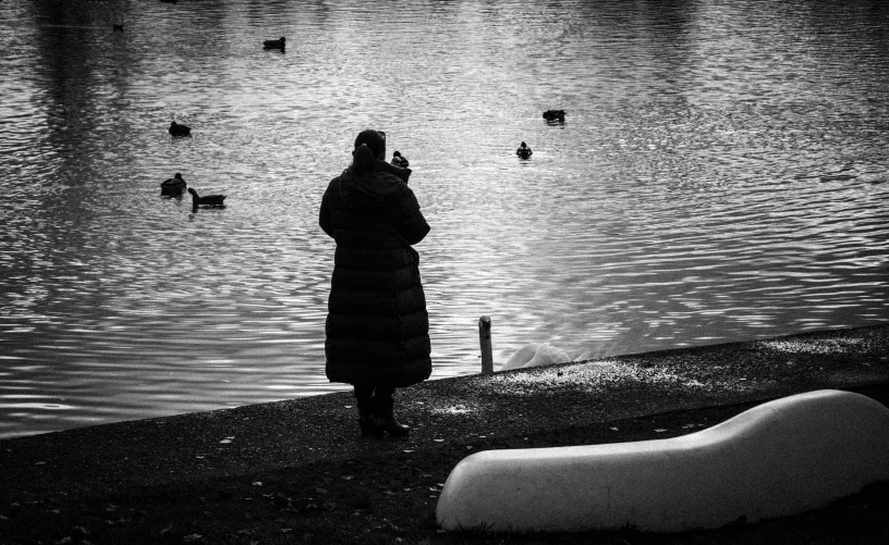 a woman stands in front of some water watching birds