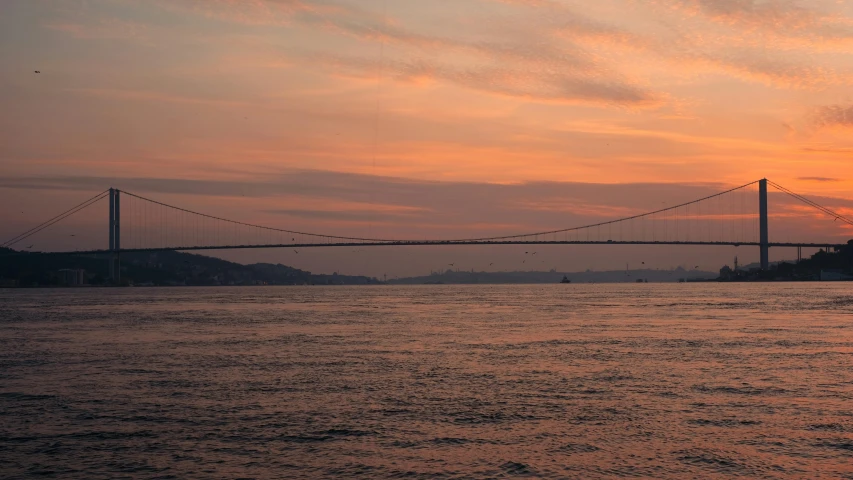 this is the sun setting over a suspension bridge
