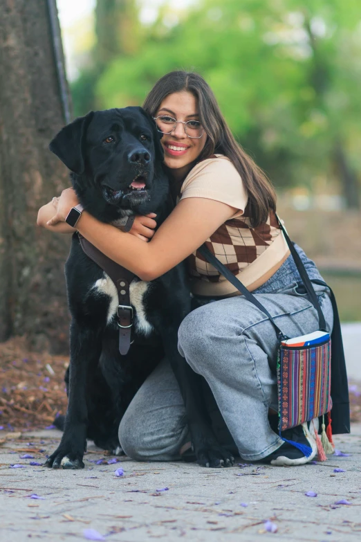 a black dog sits on its owner's lap while the woman is hugging her