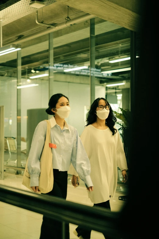 two woman wearing face masks walk together