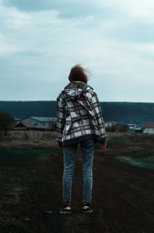 a person standing on a dirt road with their back to the camera