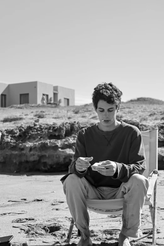 black and white pograph of boy sitting in chair eating