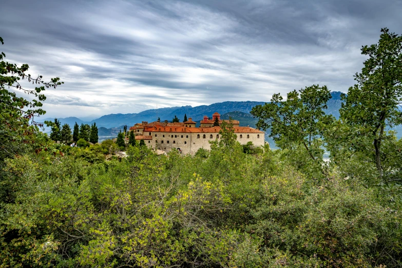 a small castle surrounded by green bushes and trees