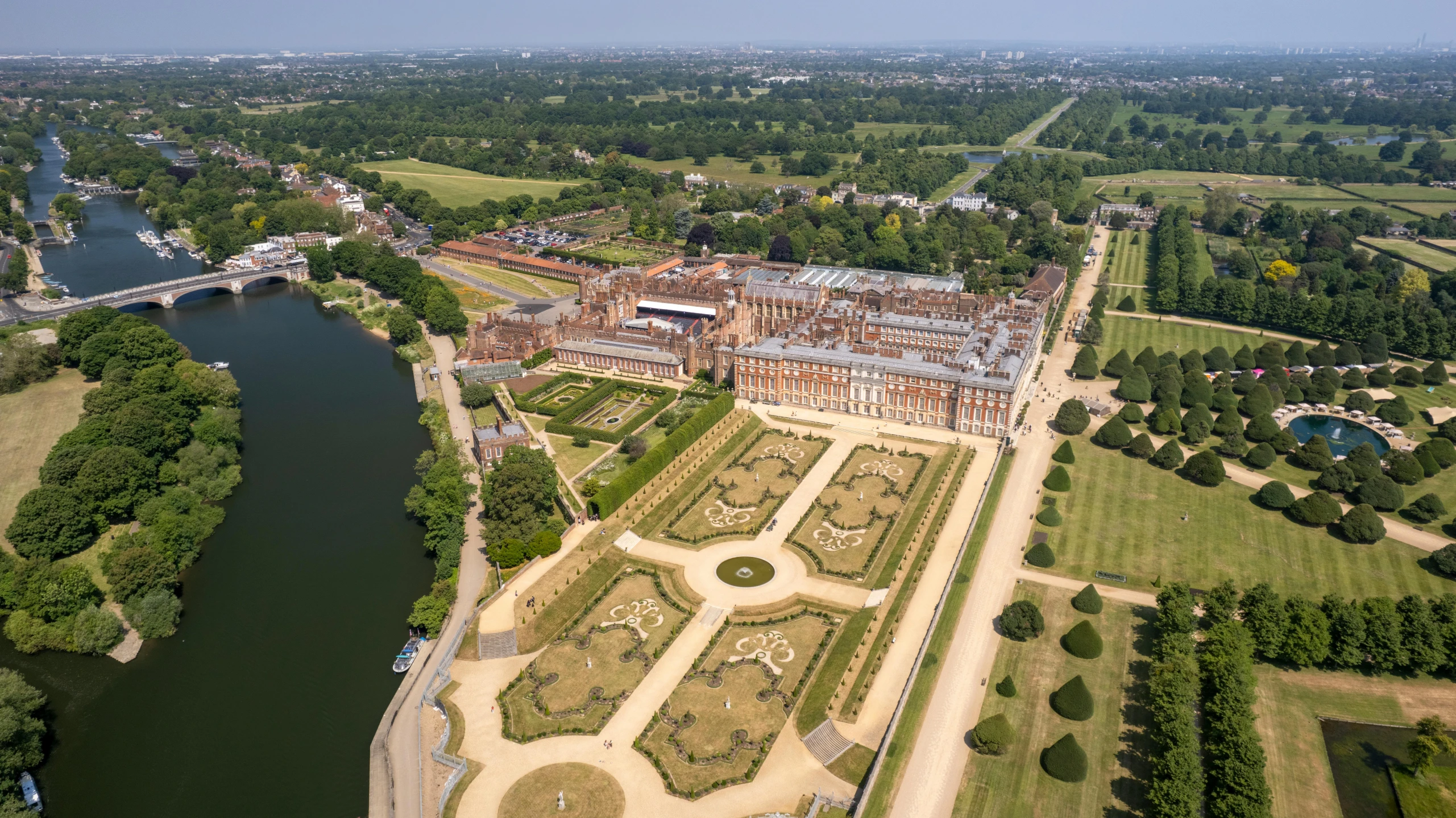 aerial po of palace with lake in foreground and gardens by waterway