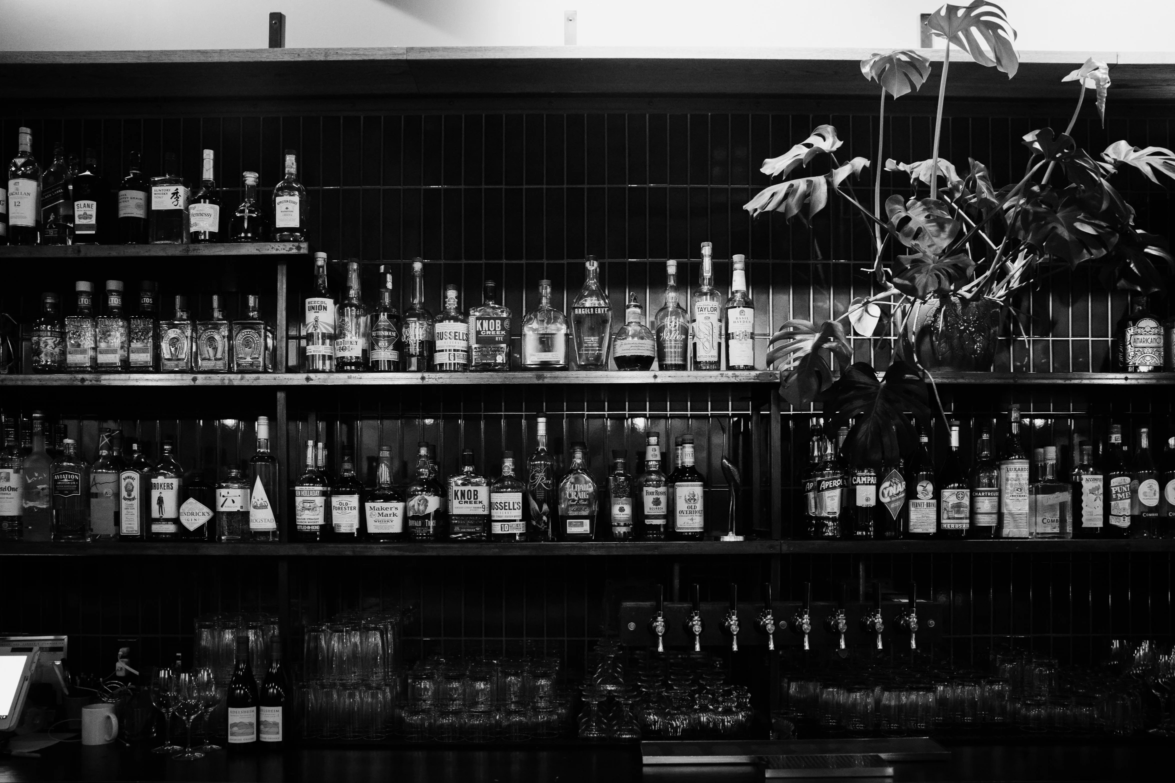 a shelf with a vase of flowers and liquor bottles