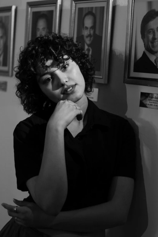 a woman with curly hair is standing in front of three pictures