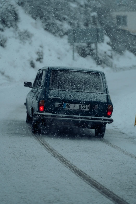 an suv driving down a snowy road on a cold day