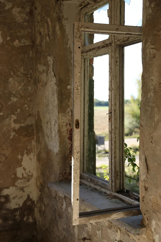 the open door to the other side of the wall shows a building that has no siding, and is partially covered with old paint