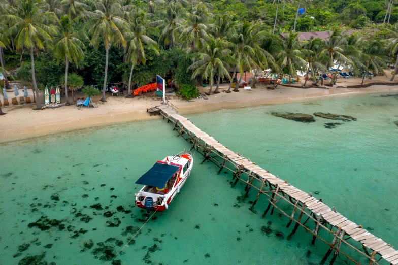 a long wooden pier that leads out to a large boat on the water