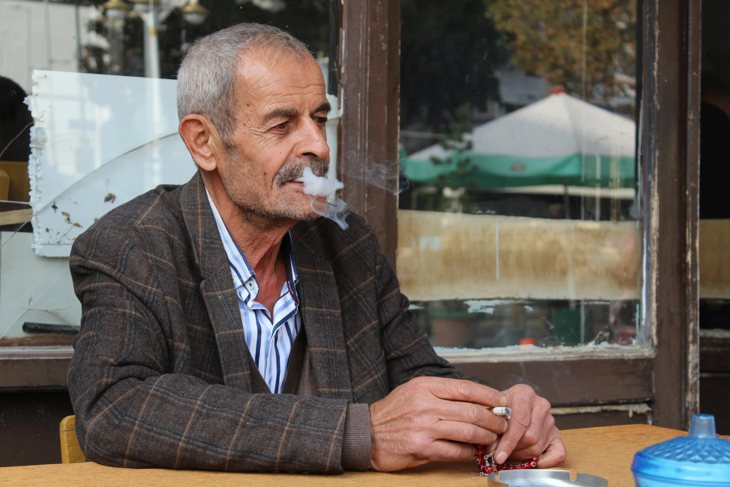 an older man is smoking a cigarette at the table