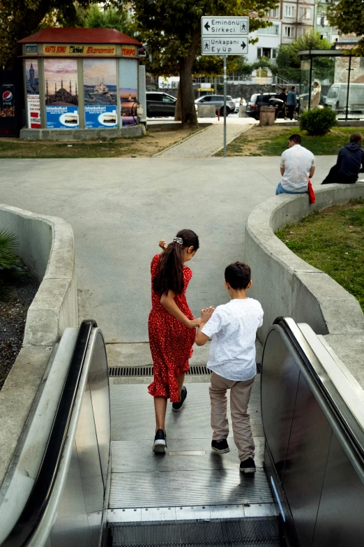 a woman and child holding hands as they ride down an escalator