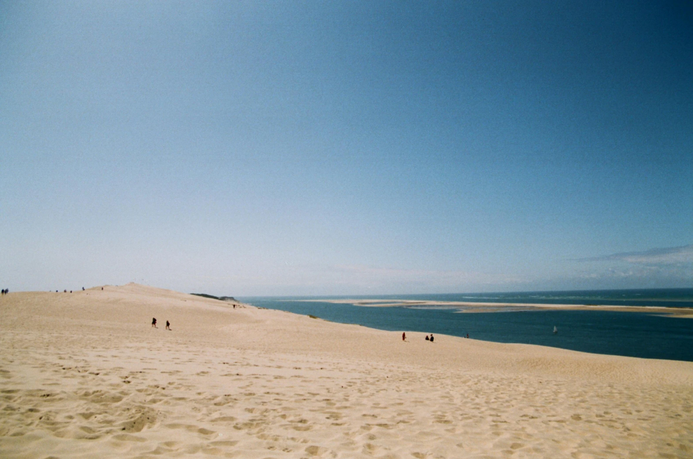 several people are on the sand dunes by the water