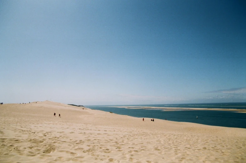 several people are on the sand dunes by the water