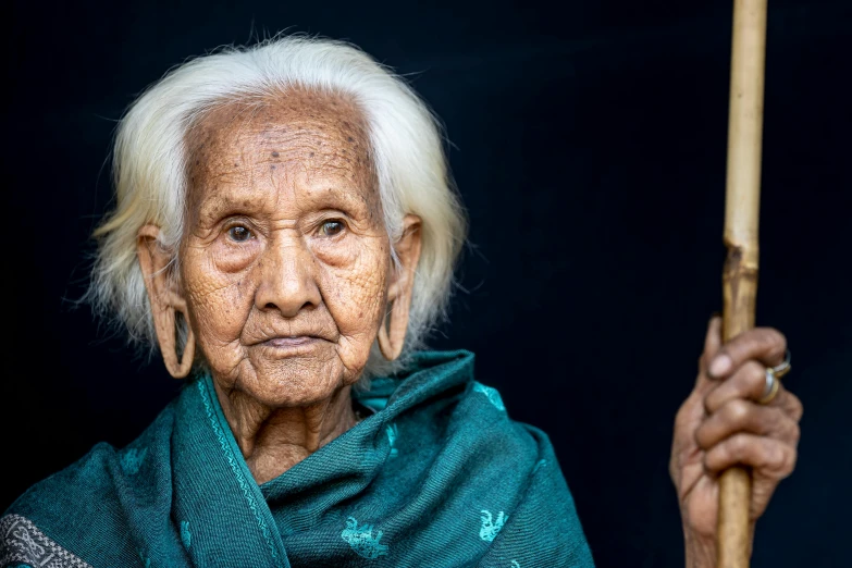 the older woman is holding a large bamboo stick