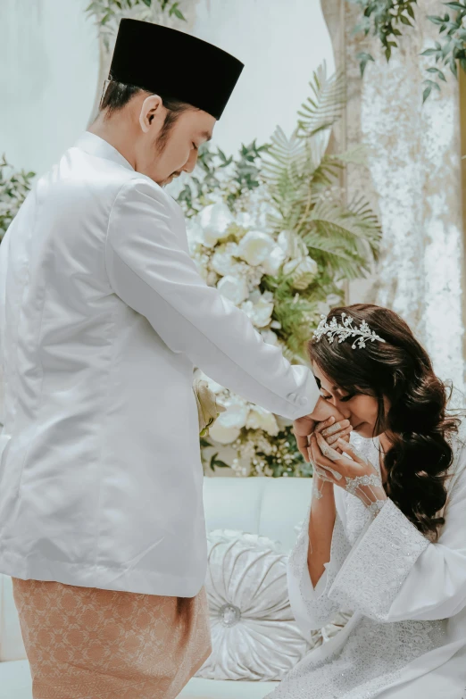 a bride and groom holding hands over their mouth