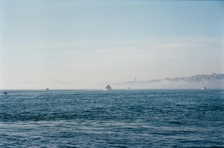 several small boats in the ocean on a foggy day