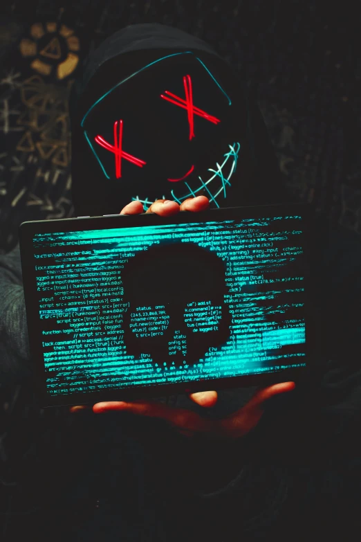 a hand holding a lit up laptop with the shape of a skull