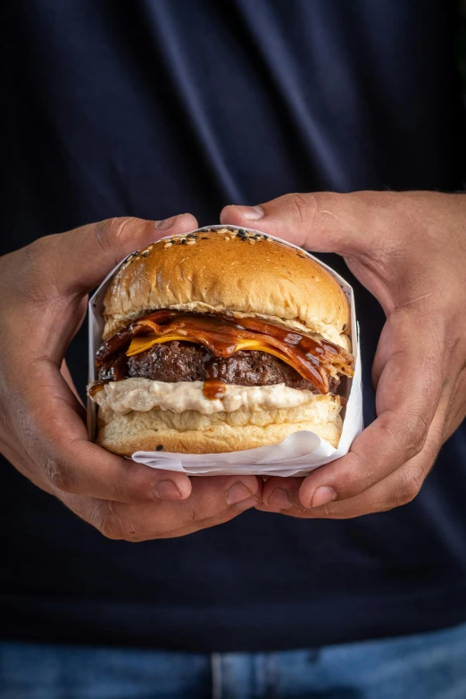 two hands holding a cheeseburger and fries