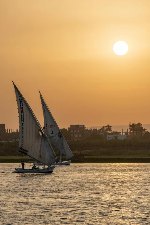 two sailboats in the ocean during sunset