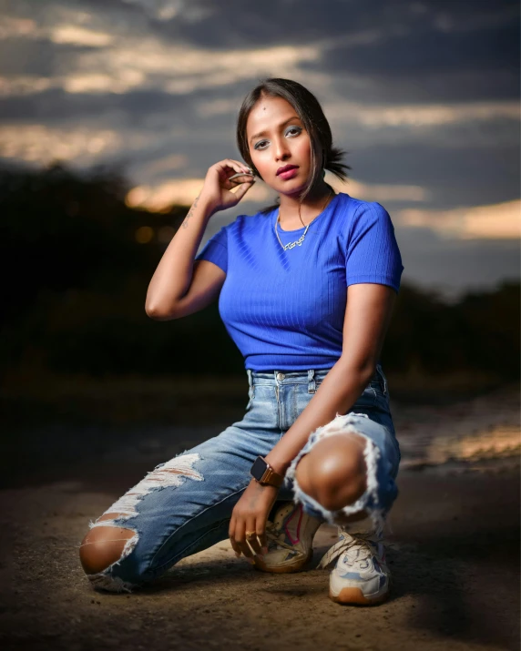 a woman sitting on the ground with her hand on her cheek