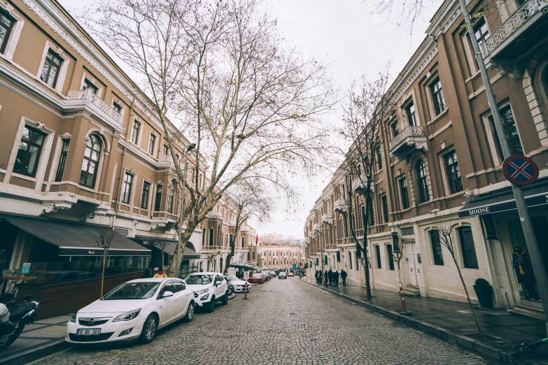 an old city street lined with vehicles and pedestrians