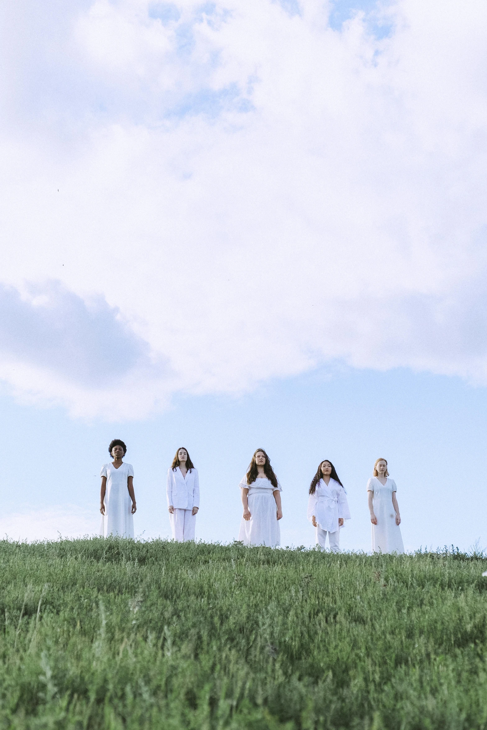 five women dressed in white standing in a field