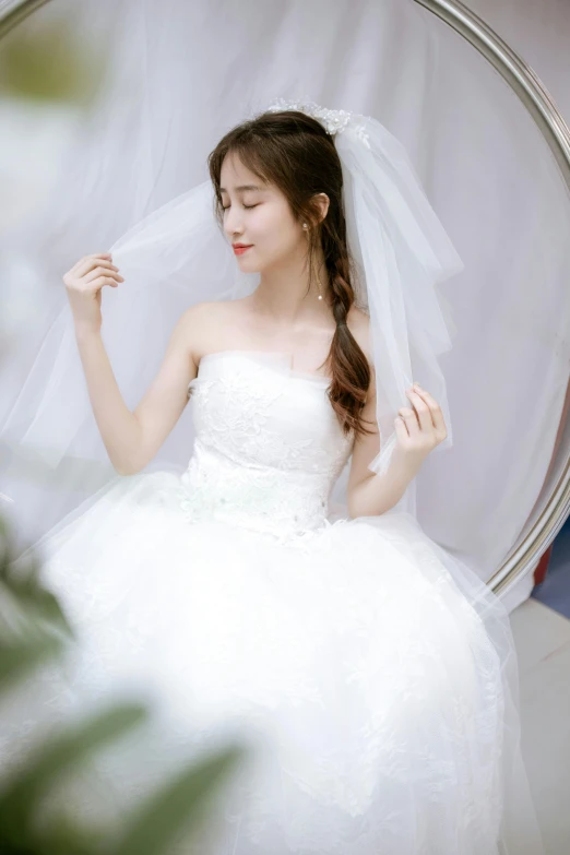 a girl in a white wedding dress sits on a round chair