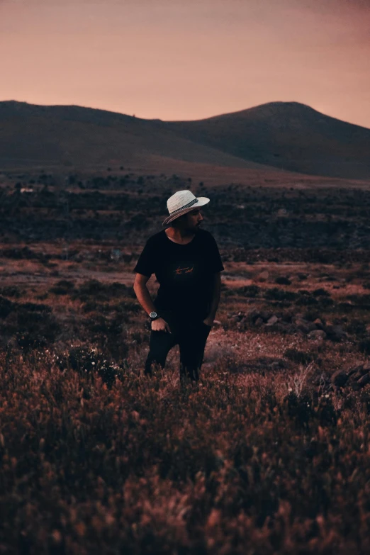 a man with a baseball cap walking through a field