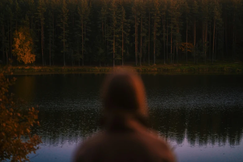 a woman looks at a small lake at night