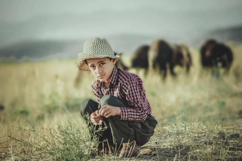 a man squatting down near some grass