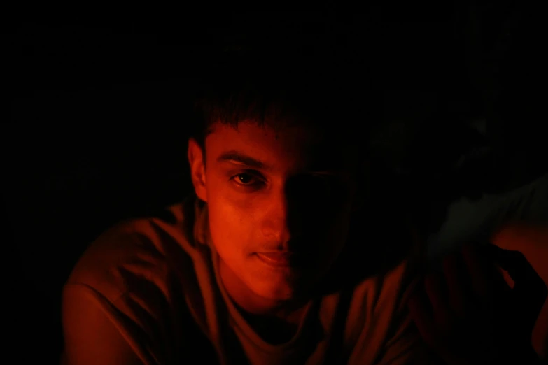 a young man standing up in a dark room