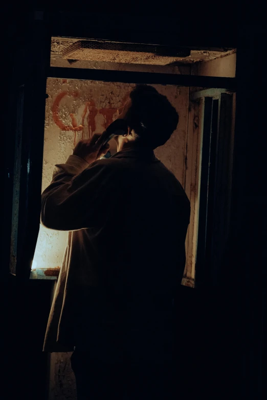 silhouette in an area of dark lighting, a person is talking on a phone