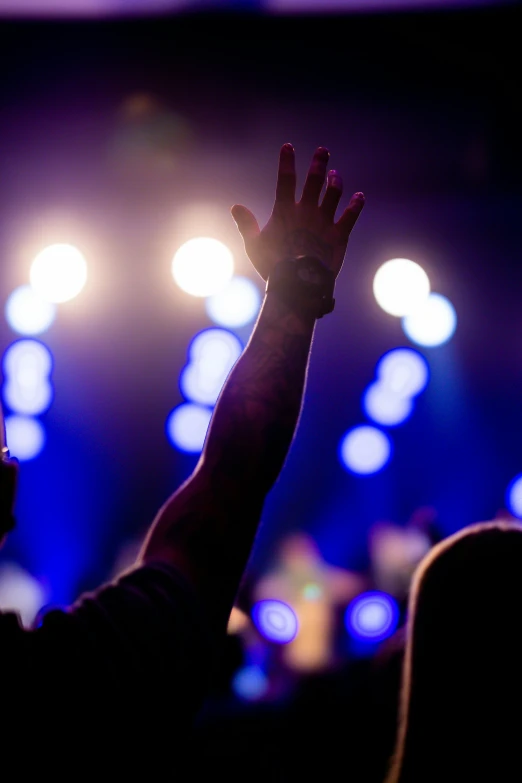 someone is raising their hands on a concert stage