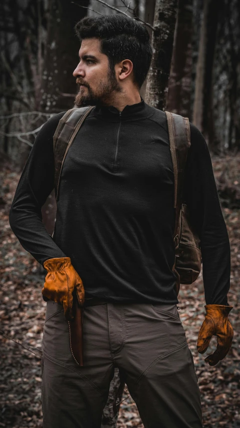 man in a dark forest with yellow gloves