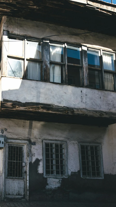 an old run down white brick house with broken windows