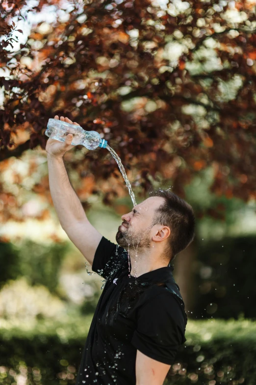 a man in black shirt standing with water pouring out of his hand