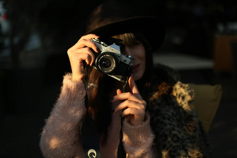 a woman is wearing a fur coat, hat and holding a camera