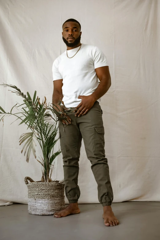 a man with beard, wearing a white t - shirt and khaki pants