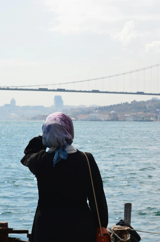 a person standing on the water looking at a bridge