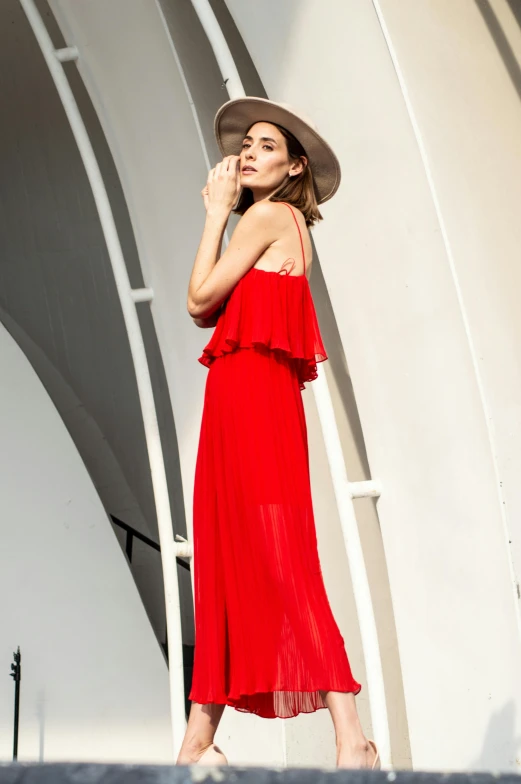 a woman with a hat is posing in front of an outdoor structure