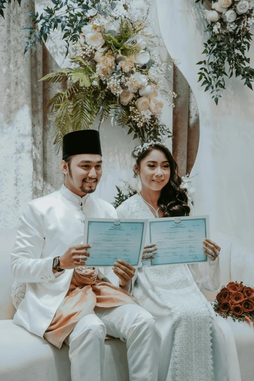 two people sitting next to each other holding a marriage certificate