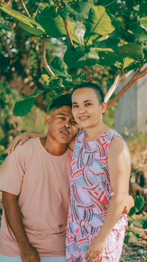 a woman emcing a man underneath a tree