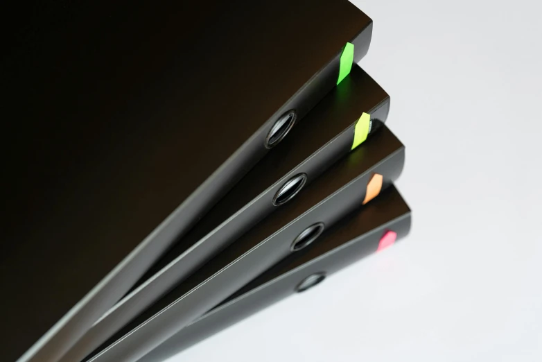a stack of black laptops with yellow and green labels