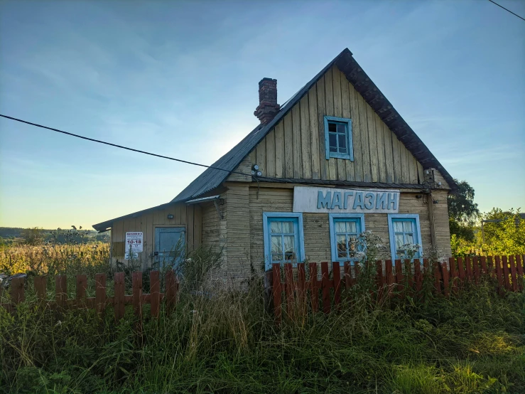 an abandoned yellow building with a picket fence around it