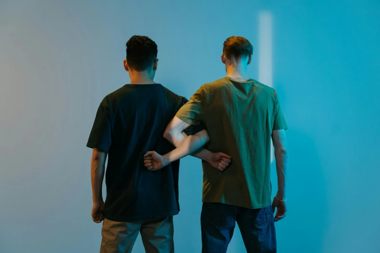 two men are standing in front of a blue wall