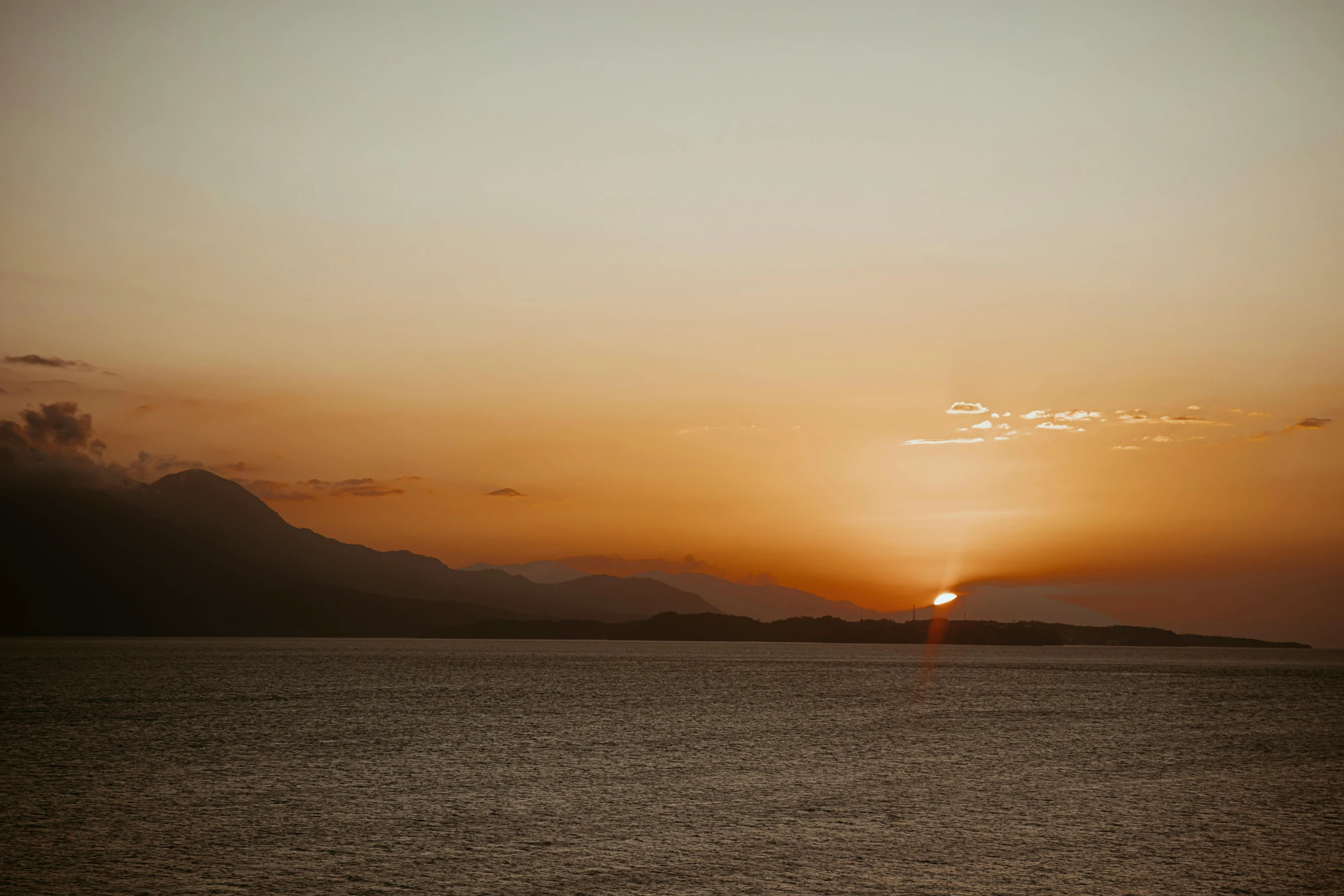 the sun is setting over the mountains on a hazy day